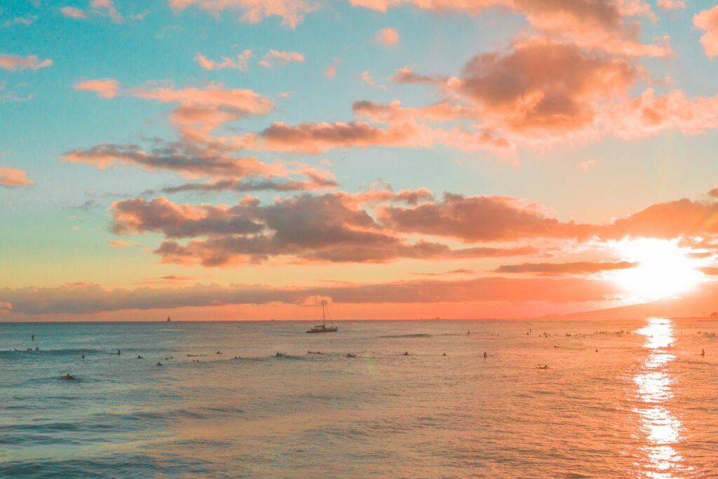 small ship out at sea with a pastel sunset